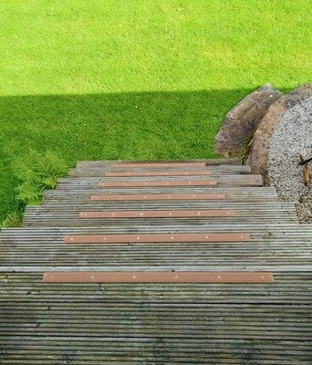 Brown anti-slip strips fitted across timber garden steps beside a lawn