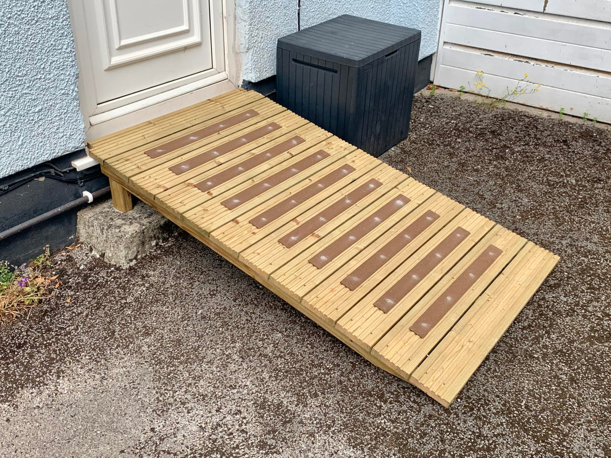 Brown anti-slip decking strips fitted across a wooden access ramp beside a doorway