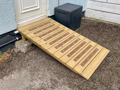 Brown anti-slip decking strips fitted across a wooden access ramp beside a doorway